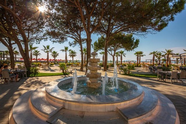 Tiered stone fountain on the shaded promenade near the beach