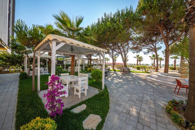 White garden gazebo with a table, framed by pink bougainvillea beside the beach path