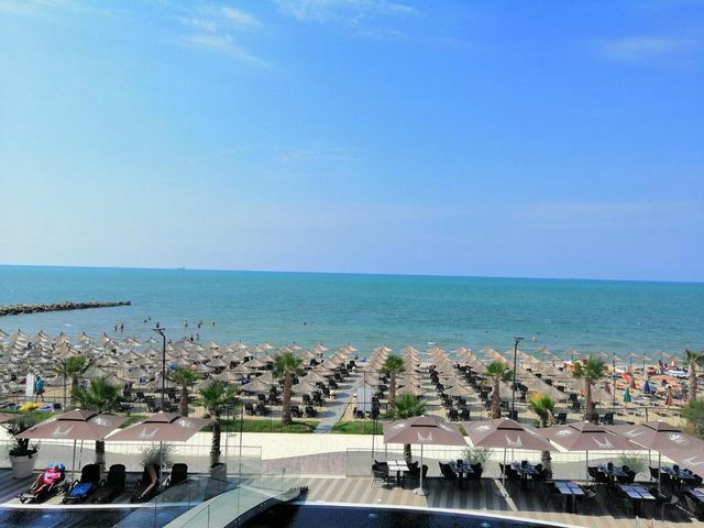 The Adriatic horizon from Qerret–Golem Beach, with rows of umbrellas and a pool edge in the foreground